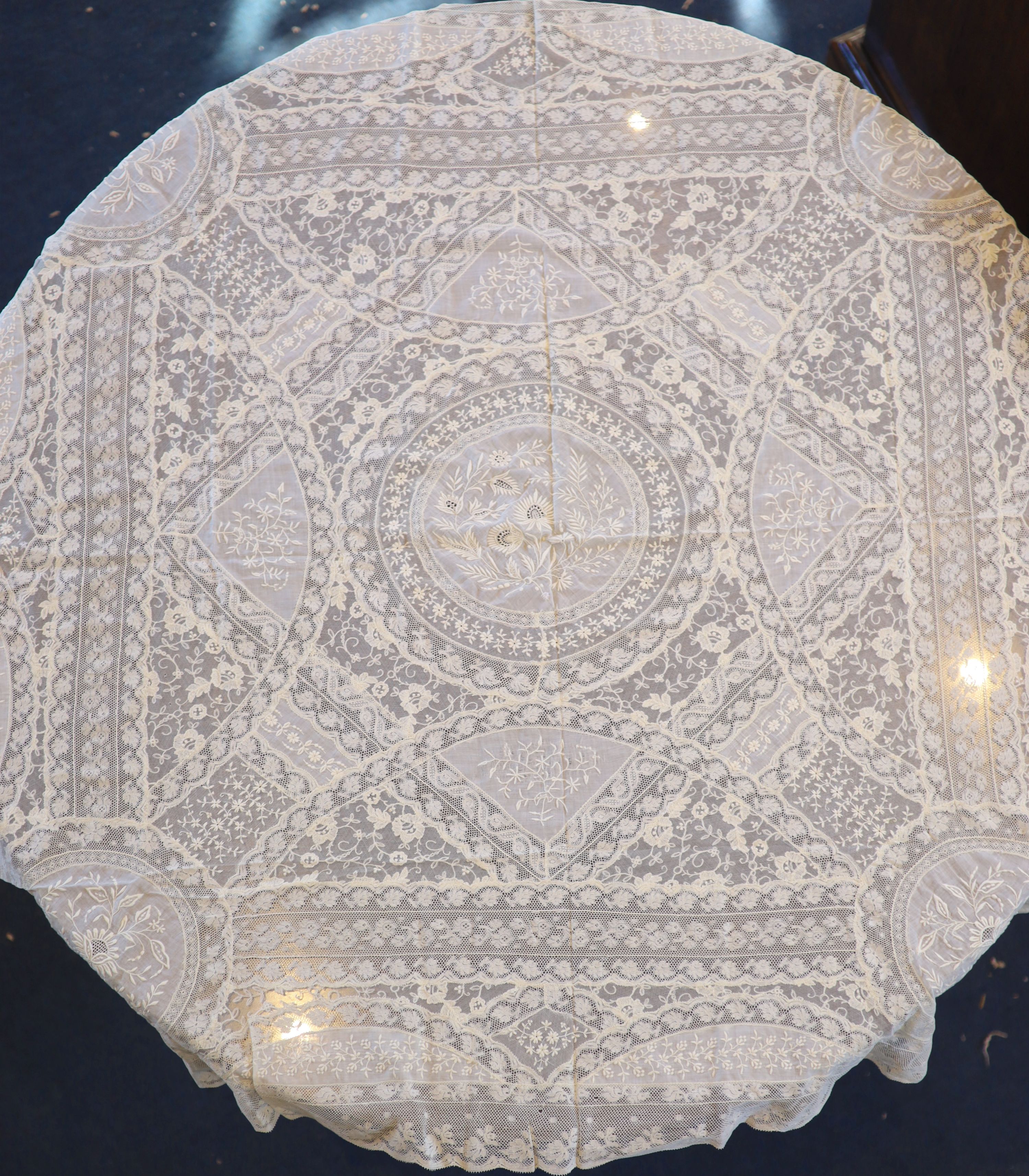 A square Normandy lace table cloth and approximately nineteen circular place mats and a centrepiece,